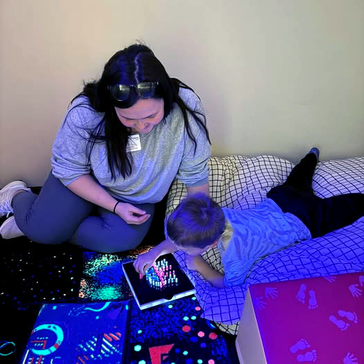 A pediatric therapist helps helping a child with a Light Bright toy in a fun, comfortable environment.