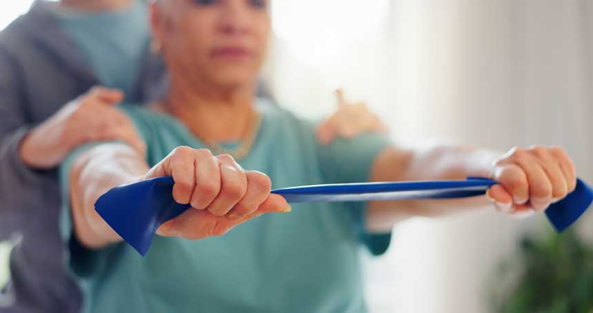 A woman works with an elastic band to improve strength and flexibility