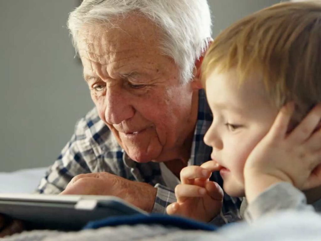 A grandfather reads a tablet with his grandson.